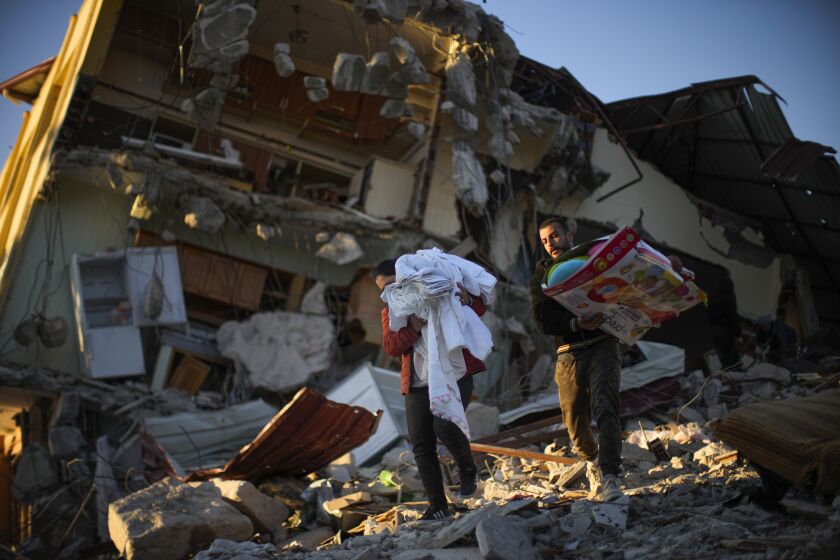 Residentes trasladan sus pertenencias desde su vivienda en un edificio destrozado por un potente sismo, en Samandag, en el sur de Turquía, el 16 de febrero de 2023. (AP Foto/Francisco Seco)