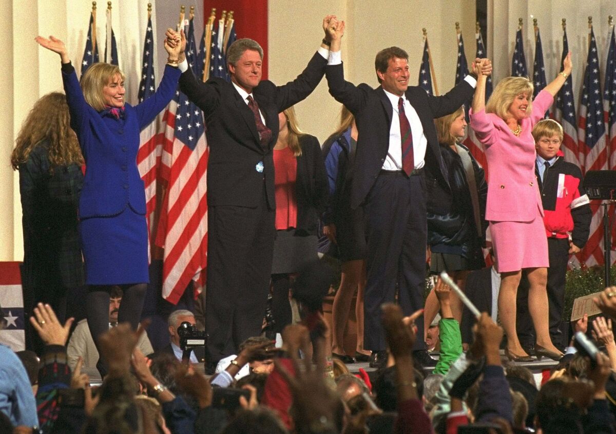 Bill Clinton and Al Gore are joined by their families and hold up their arms in front of a cheering crowd
