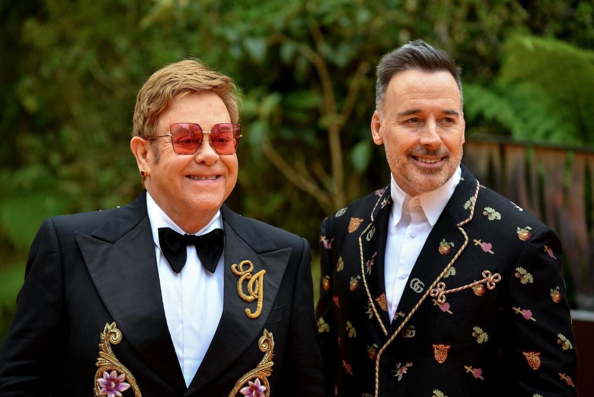 Elton John, left, and David Furnish in brightly embroidered formal wear.