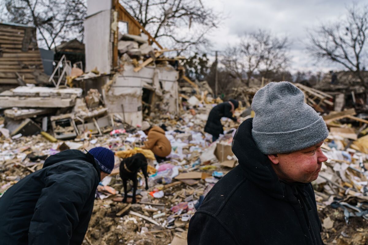 Several people clear the rubble from a home that was destroyed by a suspected Russian airstrike