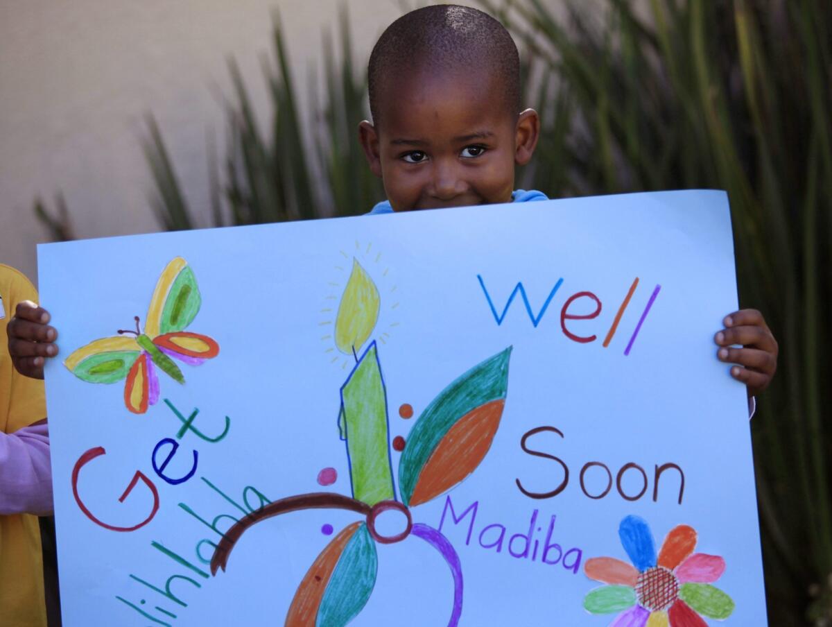 A boy holds up a get-well poster for South Africa's former president, Nelson Mandela, at his house in Johannesburg.
