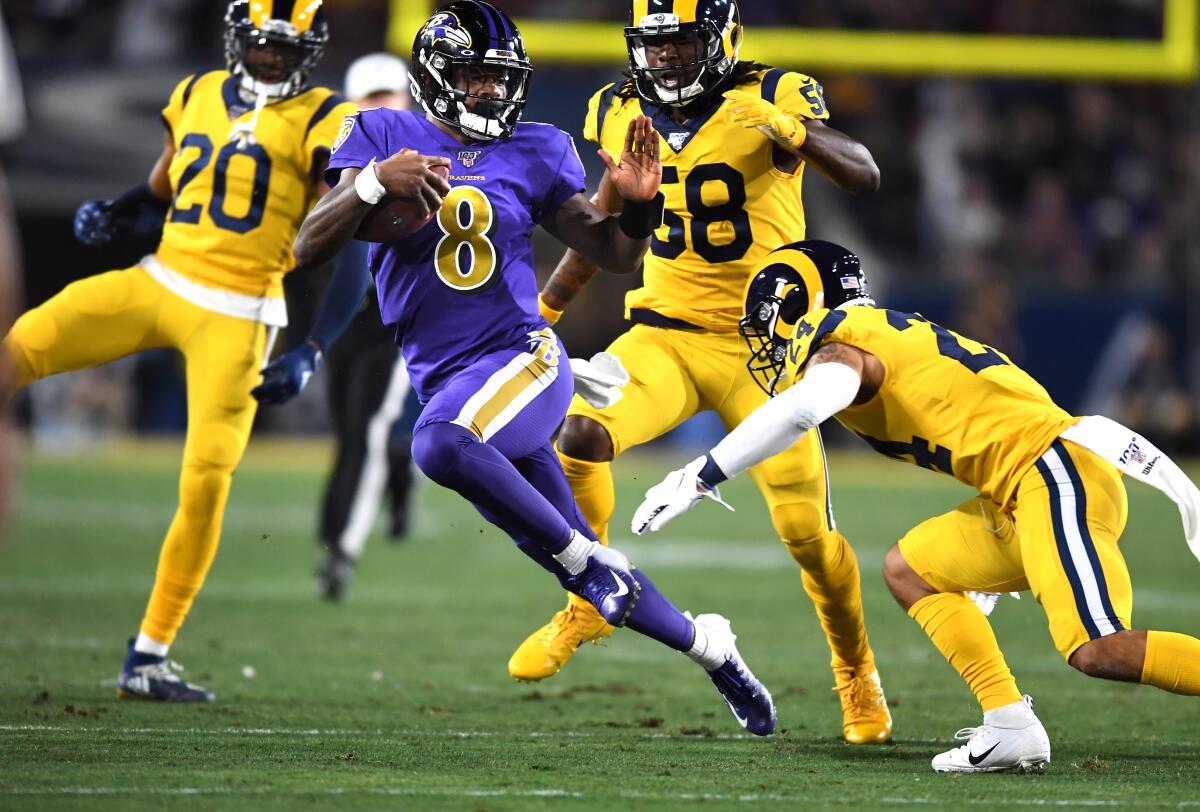 Ravens quarterback Lamar Jackson picks up a big gain against the Rams at the Coliseum.