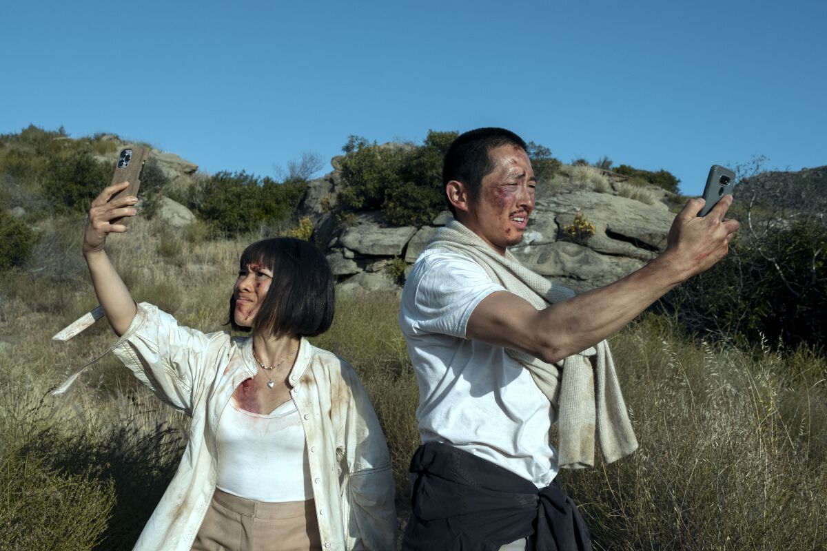Ali Wong and Steven Yeun hold their phones up, searching for a signal, in a scene from 'Beef'