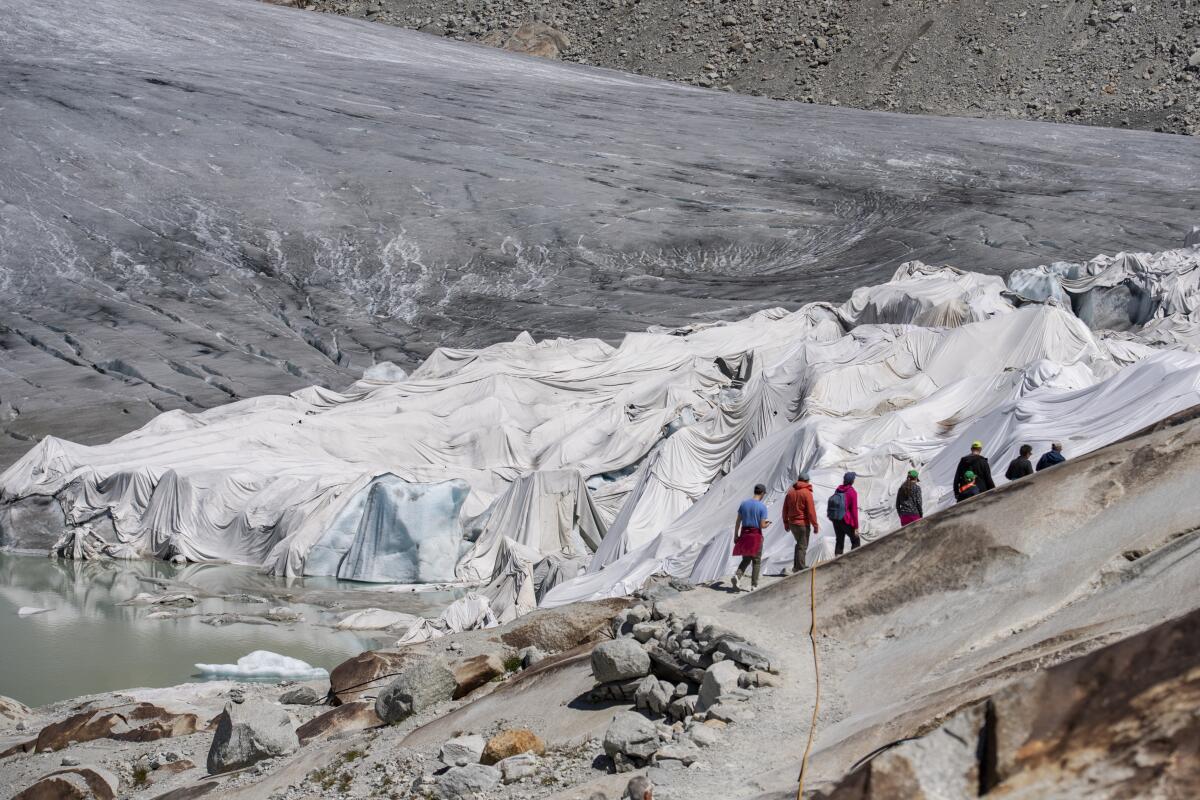 Gente visitando el glaciar de Rhone cubierto de lonas, sobre Gletsch, cerca de Furkapass en Suiza