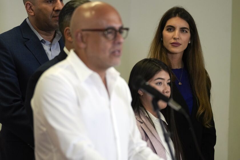 Camila Fabri, right, wife of Colombian businessman Alex Saab who was extradited to the U.S. last year, looks on as Jorge Rodriguez speaks, as part of the Venezuelan government delegation at Benito Juárez International Airport in Mexico City, Friday, Nov. 25, 2022. The government of Venezuela and its opposition are set to resume this weekend long-stalled negotiations to address their country's complex crisis. (AP Photo/Fernando Llano)