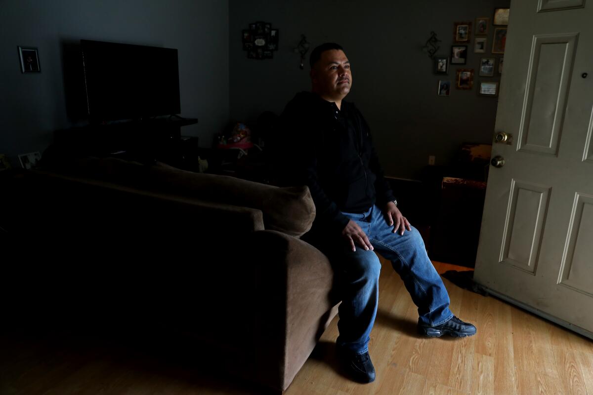 Santos Ruiz sits on a couch in his home