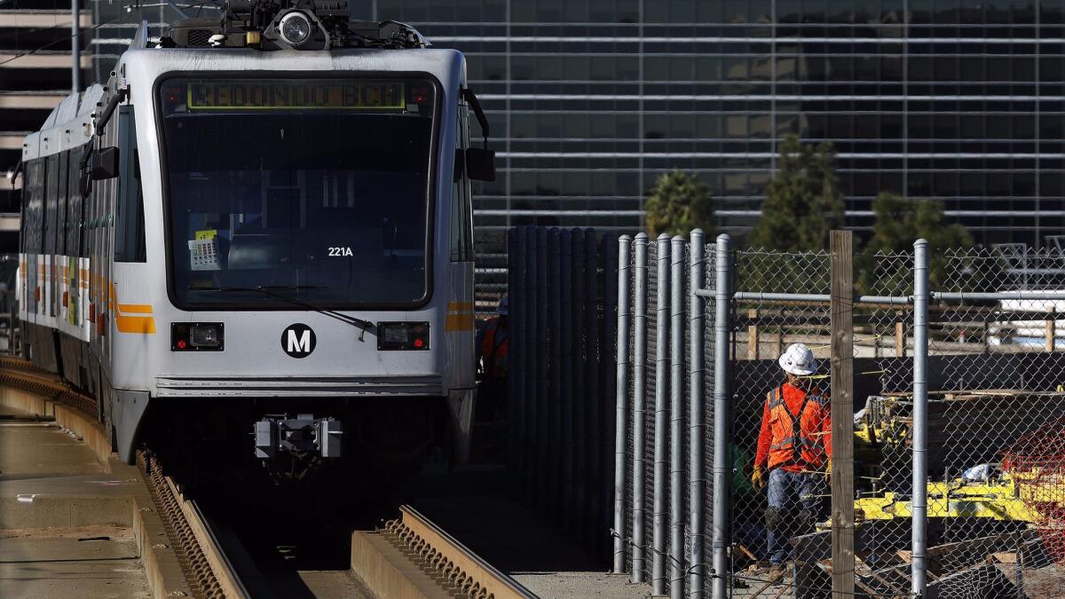 A Metro Green Line train leaves the Aviation/LAX Station in January as work is underway, at right, for the future Crenshaw/LAX line. Five Green Line stations reopened Sunday ahead of schedule.