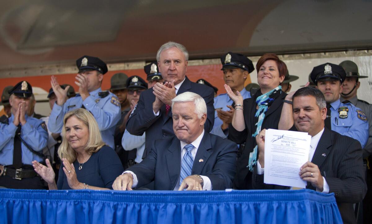 Pennsylvania Gov. Tom Corbett, center, reacts after signing the Revictimization Relief Act as Maureen Faulkner, left, widow of police officer Daniel Faulkner, and state State Rep. Mike Vereb, right, look on.
