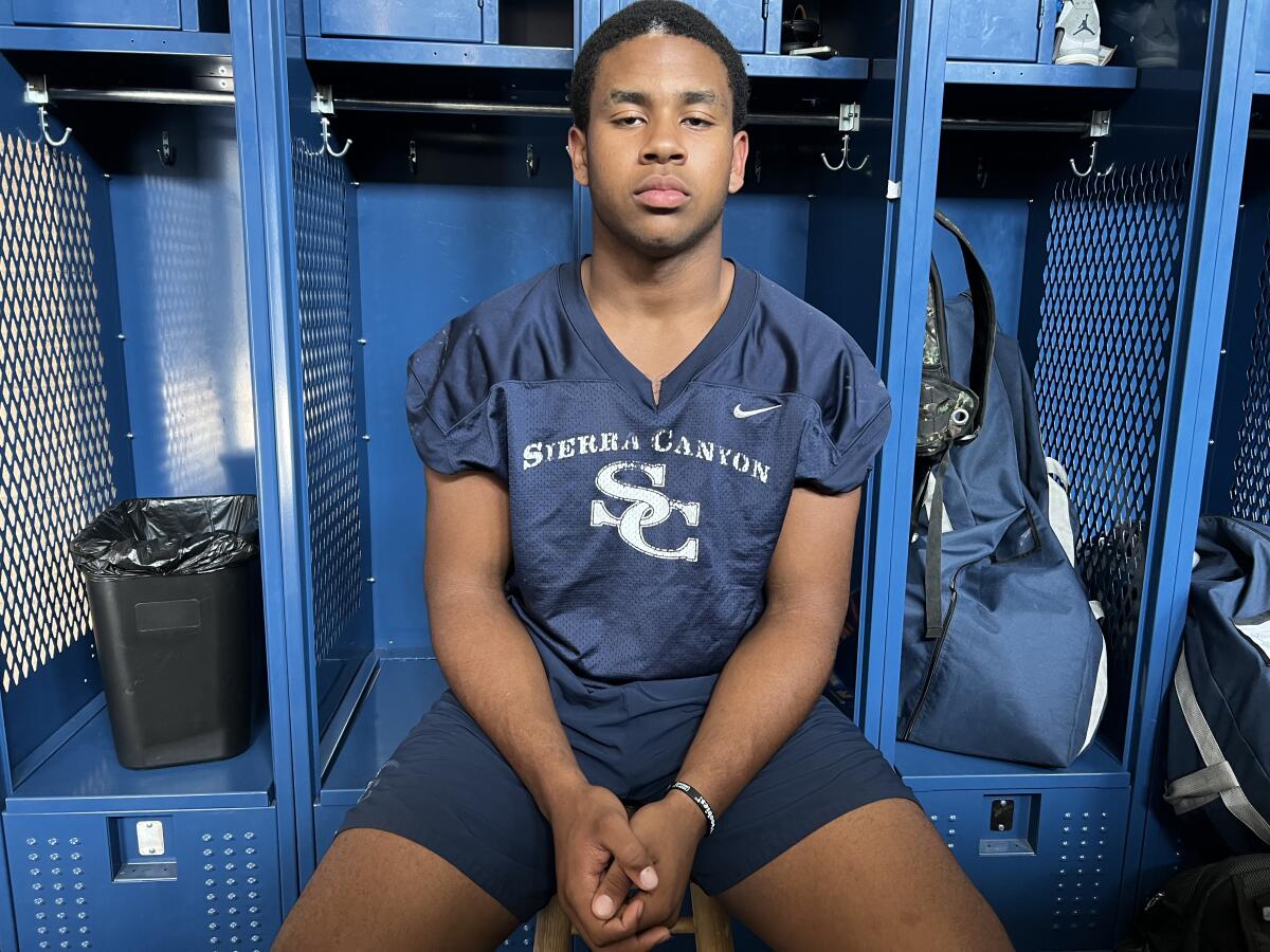 A young man wearing shorts and T-shirt sits in front of a locker