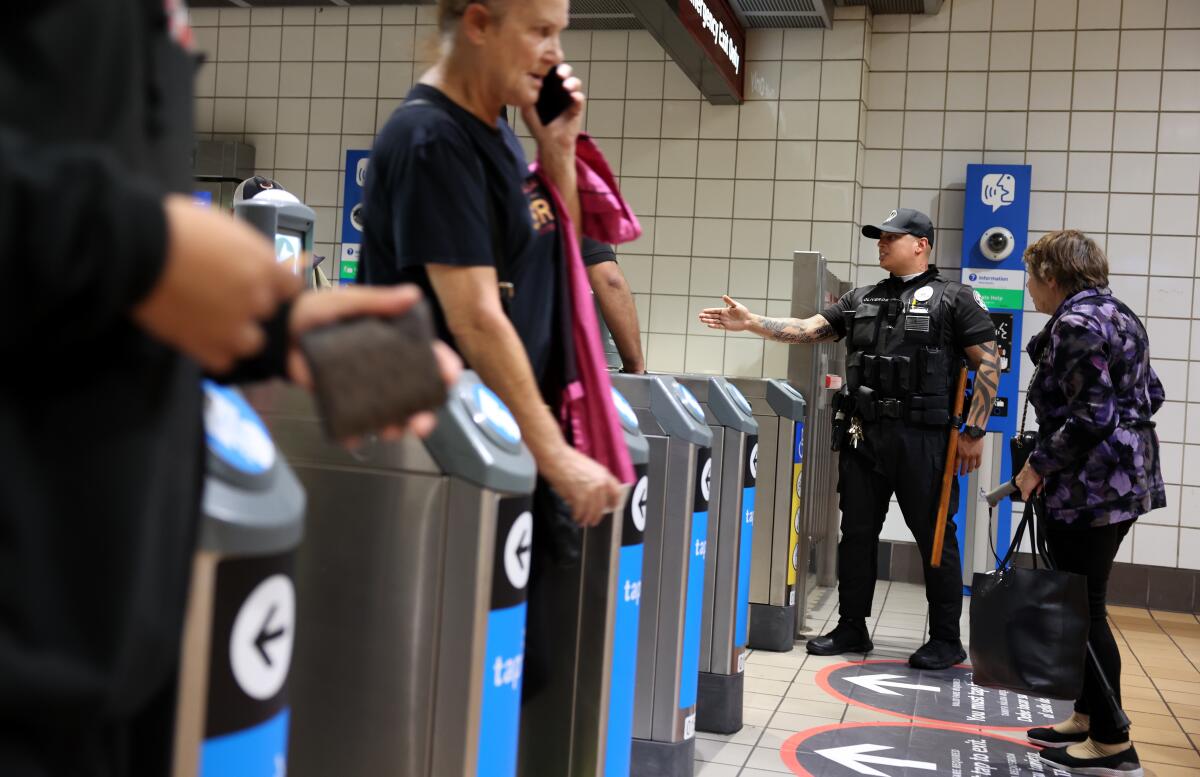 A Metro transit security officer with riders at the North Hollywood subway station on May 29 