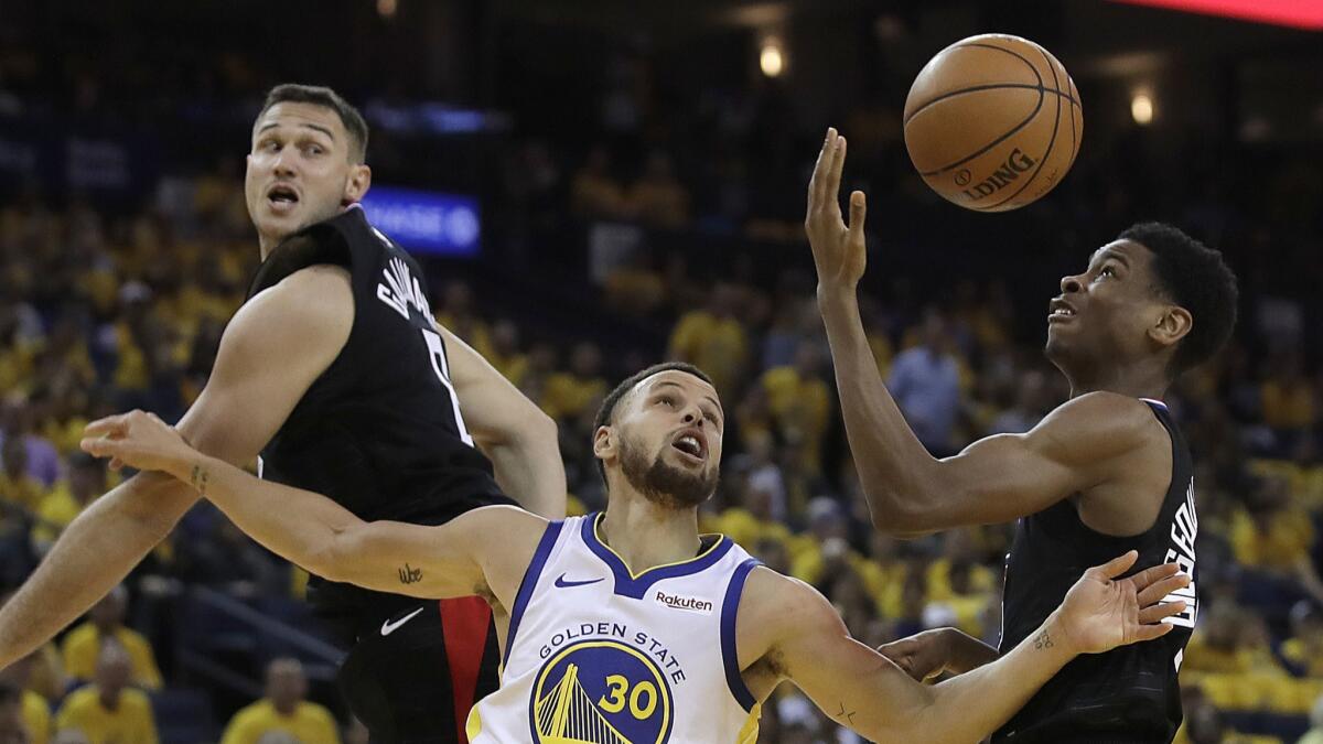 Golden State Warriors' Stephen Curry, center, and Clippers' Shai Gilgeous-Alexander, right, go for the ball during the second half in Game 1 of a first-round NBA playoff series on Saturday in Oakland.