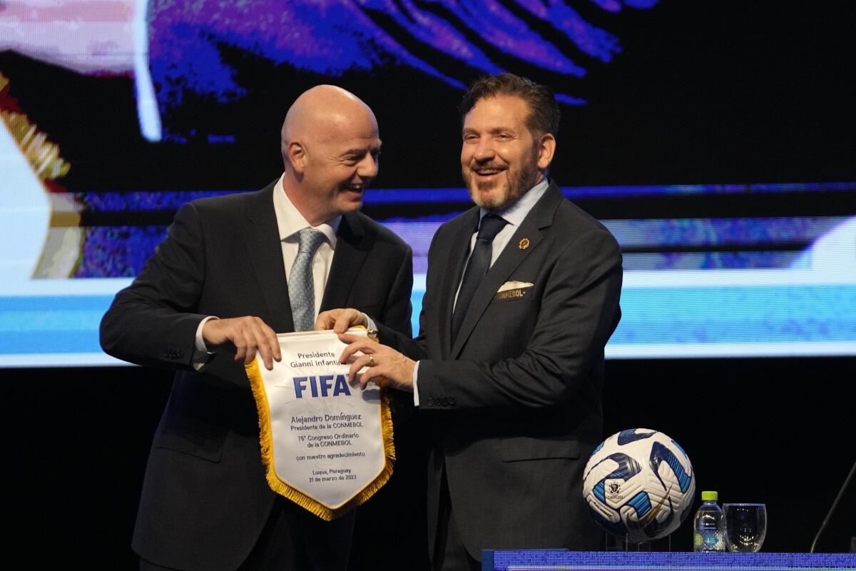 El presidente de la FIFA Gianni Infantino (izquierda) entrega un banderín al líder de la CONMEBOL 