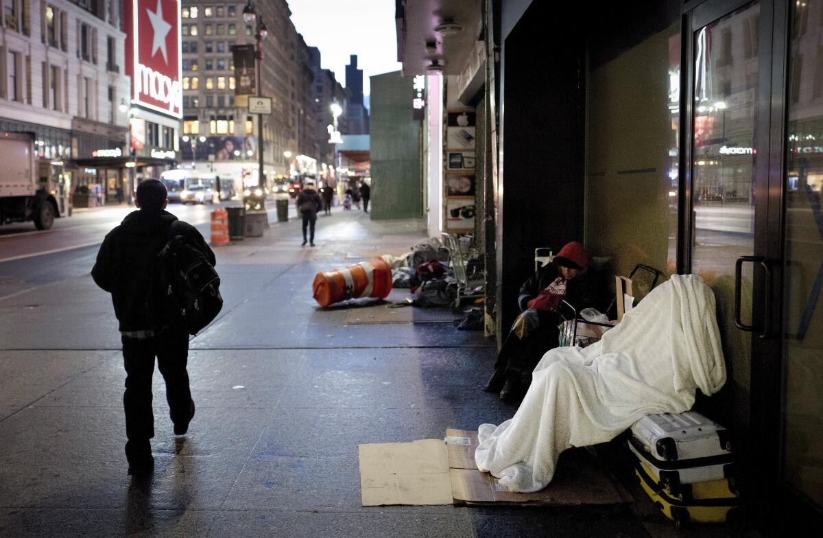 ARCHIVO _ En esta foto , un indigente duerme bajo una manta en una acera en Nueva York.