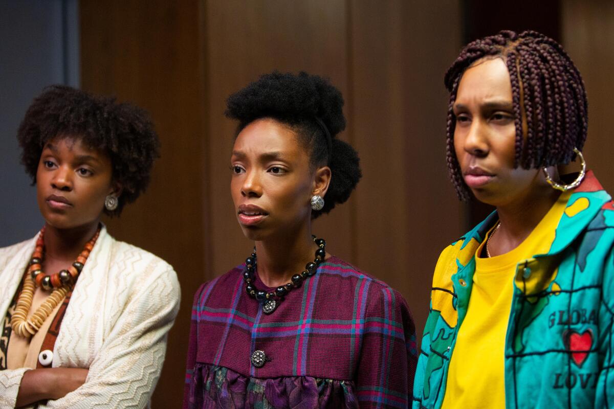 Three Black women wear 1980s period clothes and hairstyles.