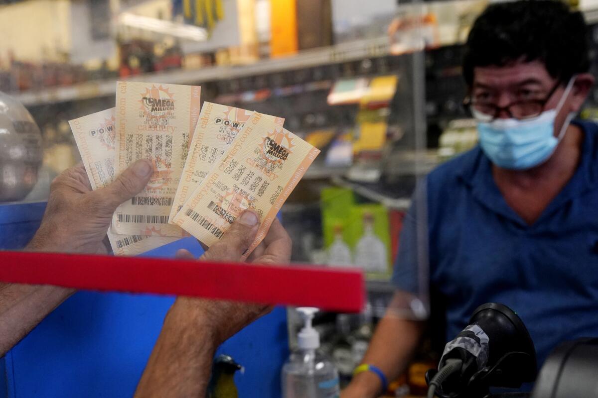 A customer holds up Powerball tickets at a store near a staff member