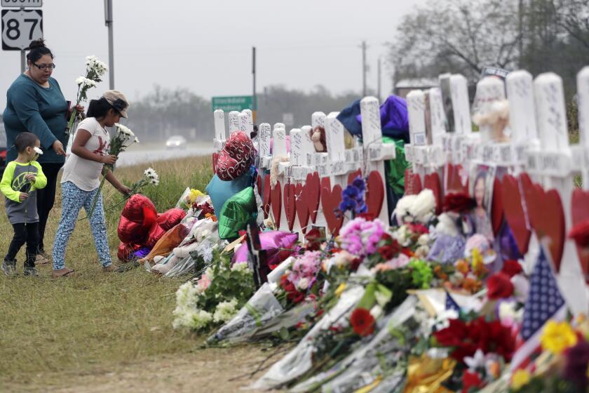 FILE - Christina Osborn and her children Alexander Osborn and Bella Araiza visit a makeshift memorial for the victims of the shooting at Sutherland Springs Baptist Church, Nov. 12, 2017, in Sutherland Springs, Texas. The Justice Department said Wednesday, April 5, 2023, that it has tentatively settled a lawsuit over the 2017 mass shooting at a Texas church that will pay victims and their families more than $144 million. (AP Photo/Eric Gay, File)