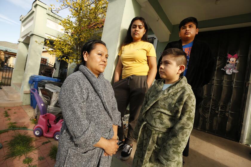 LOS ANGELES, CA - MARCH 25, 2020 Raquel Lezama outside her home in Los Angeles before walking with her daughter Monica Ramos, 19, to Manual Arts High School to pick up grab-and-go meals for the family. Raquel Lezama with her family is struggling economically to survive the coronavirus Covid19 pandemic. Raquel Lezama was laid off from her $17.76 an hour job as a mini-bar attendant at a luxury Beverly Hills hotel on Friday March 13. She is a single mother of three children, an unemployed 19-yr-old daughter (Monica Ramos) and two sons: Alan, a 13-year-old with a learning disability and Jesus, an 8 year old with colitis. She has a copy of her termination notice from the hotel. She waited five hours in line at her union hall to get help filing unemployment but that won't cover her rent, her car loan and other bills. Alan is having a hard time doing his homework on line, and Jesus has a packet from his teacher. They play video games and watch TV and are learning how to cook. (Al Seib / Los Angeles Times)