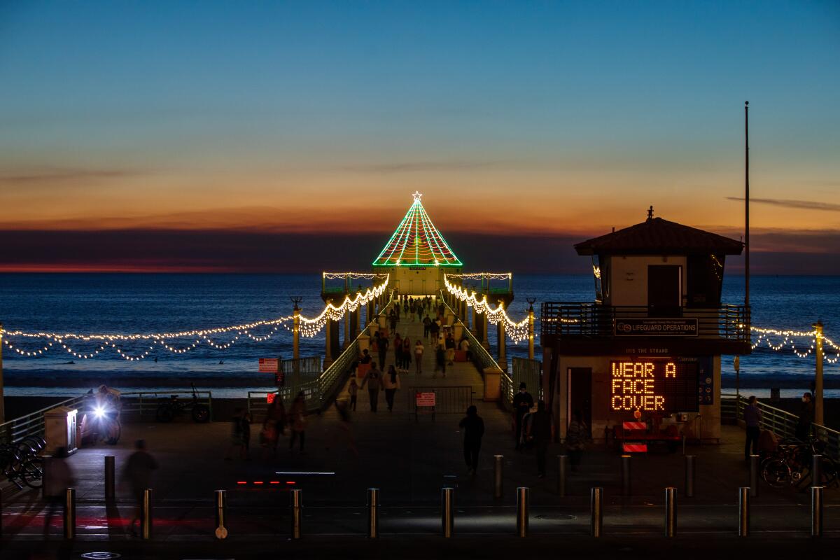 With annual holiday decorations on display, a city sign alerts visitors to the Pier in Manhattan Beach, CA.