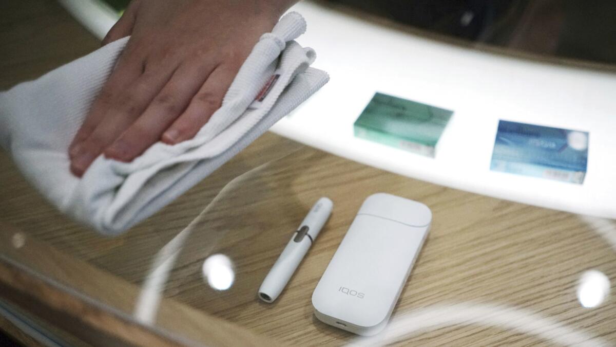 A staffer cleans an IQOS display at store in Tokyo.