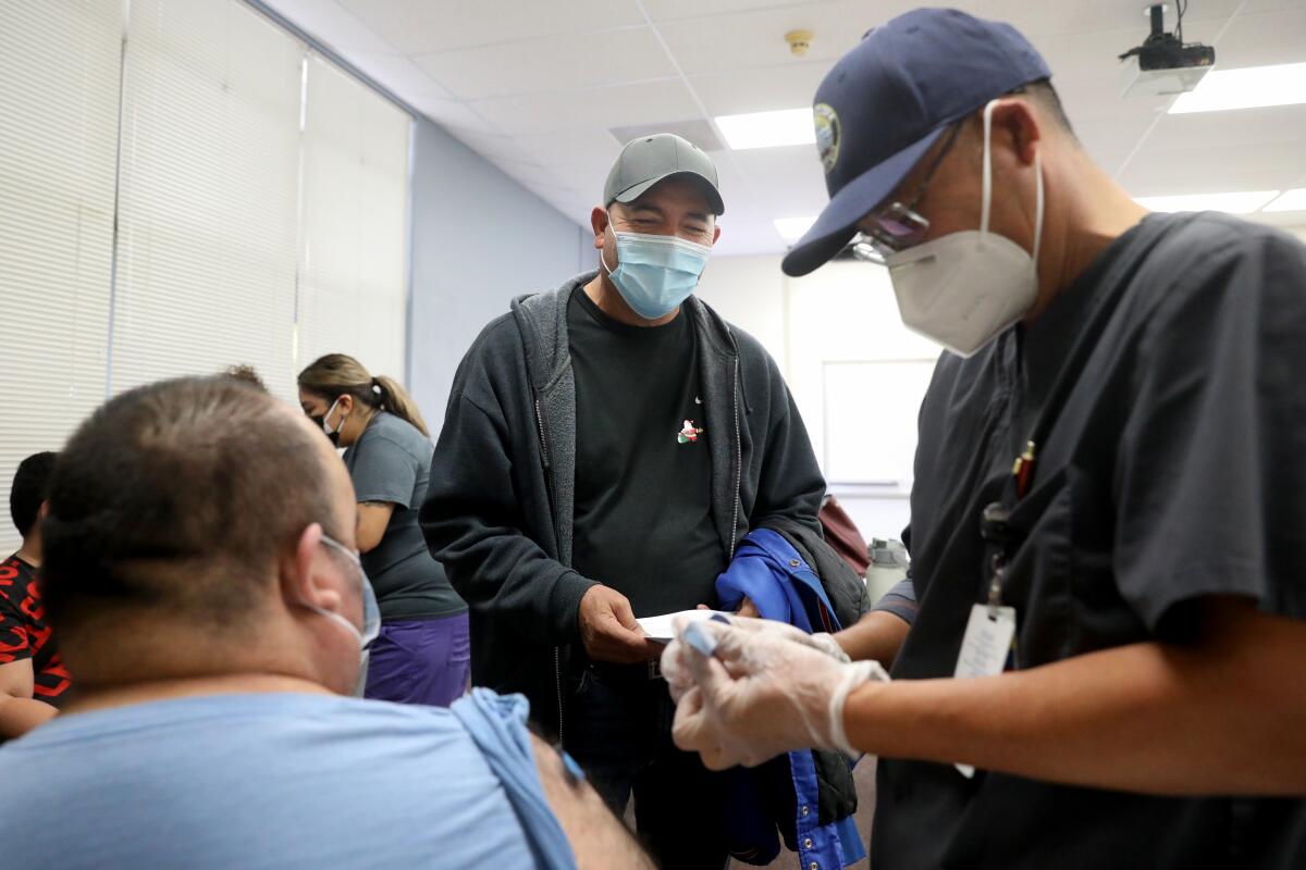 Enrique Cortes of Delano watches his brother Armando Cortes receive a booster shot