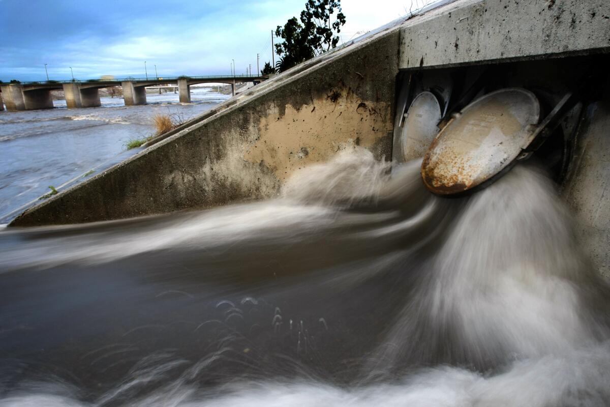 Stormwater bursts through heavy steel gate valves and flows into the Los Angeles River in Long Beach.