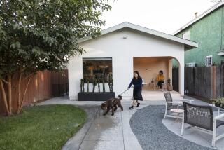 A woman walks a dog in front of a house.