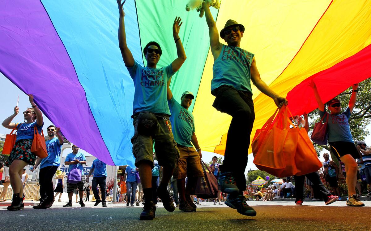 Parade participants dance under a giant rainbow flag on Santa Monica Boulevard in West Hollywood during the 2014 L.A. Pride Parade.