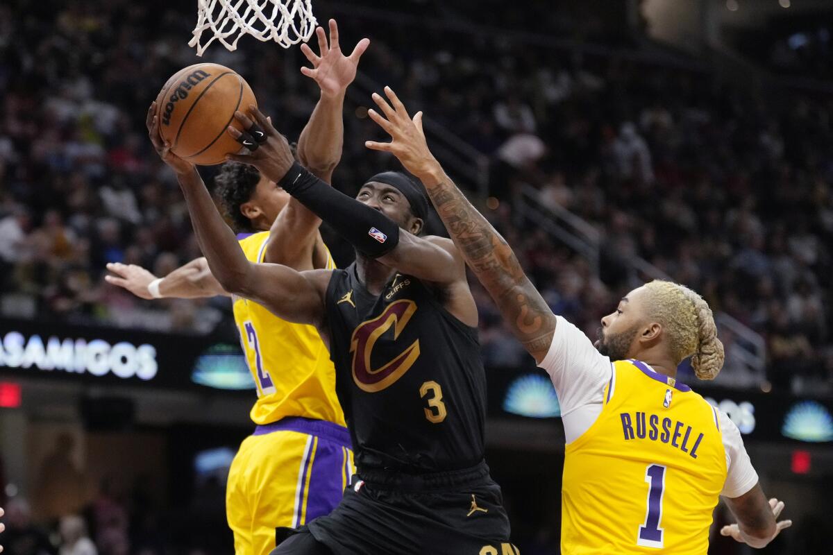 Cavaliers guardı Caris LeVert, Çarşamba günü Cleveland'da Lakers guardı Max Christie ile guard D'Angelo Russell arasında şut atıyor.