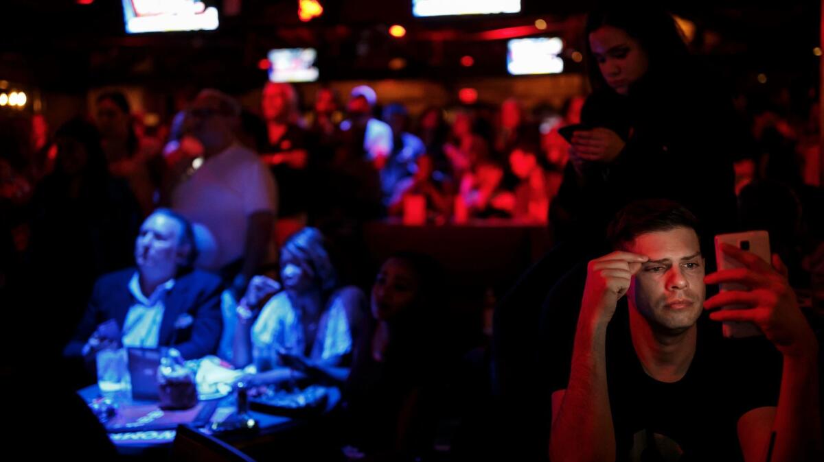 Hillary Clinton supporters check their mobile devices for the latest presidential election results at a election night party at The Abbey, in West Hollywood, Calif., on Nov. 8, 2016.