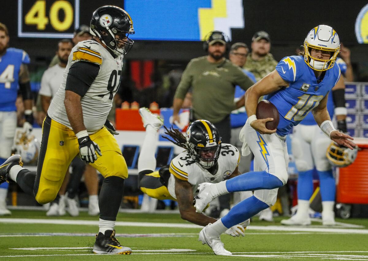 Chargers quarterback Justin Herbert (10) runs past Steelers players for a first down 