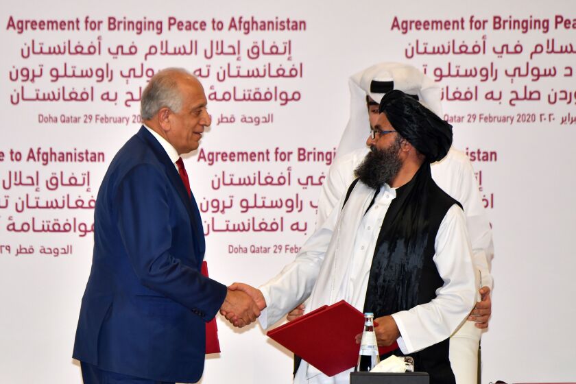 TOPSHOT - (L to R) US Special Representative for Afghanistan Reconciliation Zalmay Khalilzad and Taliban co-founder Mullah Abdul Ghani Baradar shake hands after signing a peace agreement during a ceremony in the Qatari capital Doha on February 29, 2020 - The United States signed a landmark deal with the Taliban, laying out a timetable for a full troop withdrawal from Afghanistan within 14 months as it seeks an exit from its longest-ever war. (Photo by Giuseppe CACACE / AFP) (Photo by GIUSEPPE CACACE/AFP via Getty Images)
