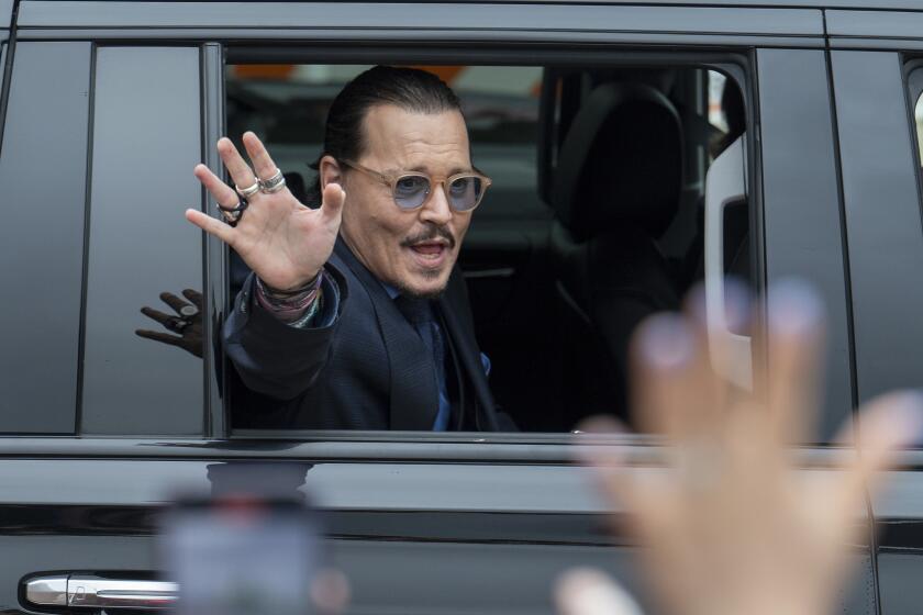 Johnny Depp in sunglasses waving his hand out of an SUV
