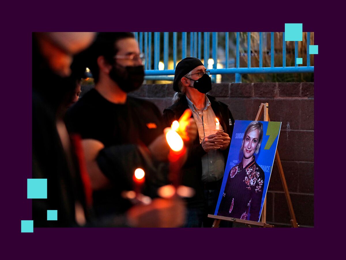 People hold candles around a portrait of a woman at a vigil.