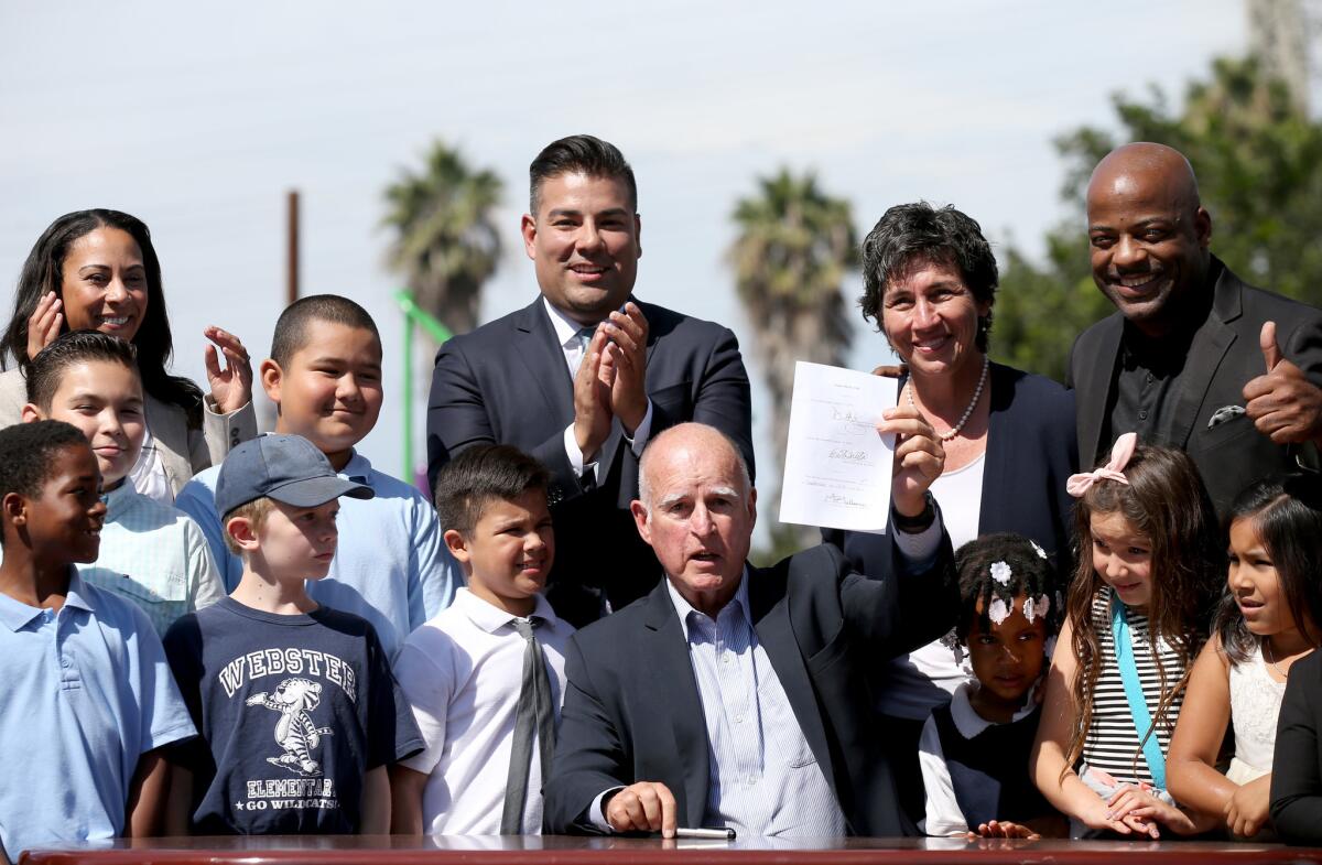 Gov. Jerry Brown signs SB 1383, a law to impose new reductions on soot and other pollution, in an event in Long Beach.