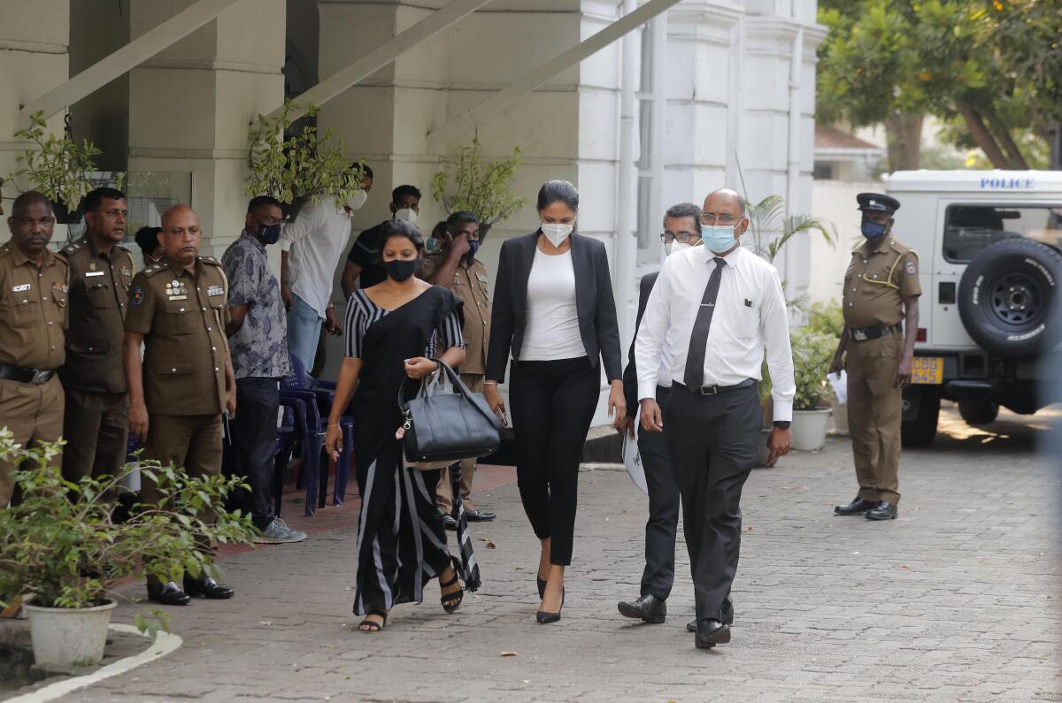 Mrs. World 2019 Caroline Jurie, center, leaves a police station after obtaining bail in Colombo, Sri Lanka, Thursday, April 8, 2021. Jurie's decision to remove the crown from the the winning Mrs. Sri Lanka contestant on stage moments after the winner was announced, because of claims she was a divorcee, drew widespread social media condemnation. The winner Pushpika de Silva who was crowned again later had complained to police that her head was wounded when the clips of her crown were removed by Jurie. (AP Photo/Eranga Jayawardena)