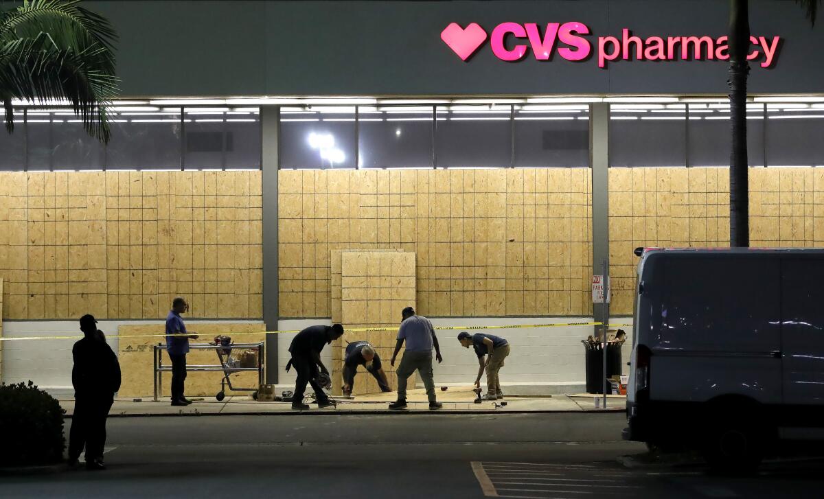 Workers board up a CVS Pharmacy on Bristol Street, right across from South Coast Plaza on Monday.