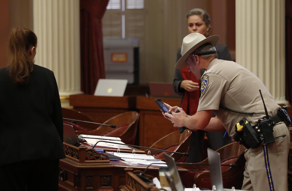 A California Highway Patrol Officer photographs a desk on the Senate floor after a red liquid was thrown from the Senate Gallery.