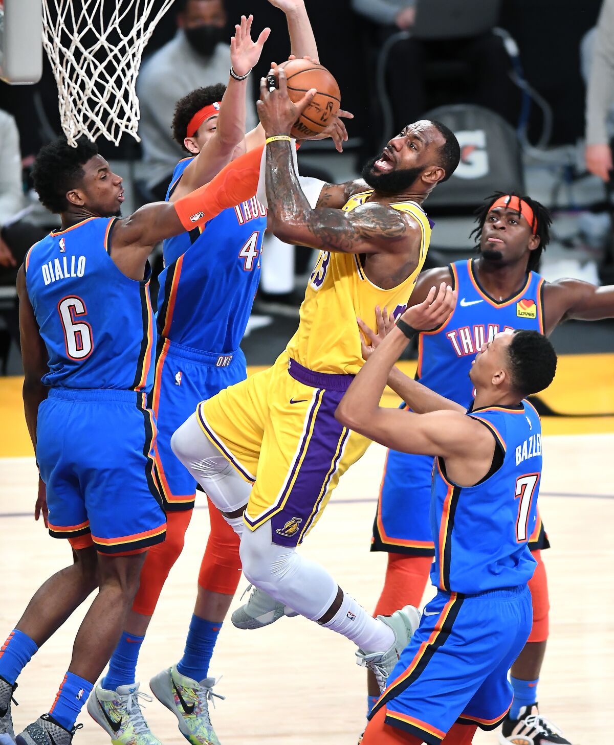 The Lakers' LeBron James beats four Thunder defenders to score a basket.