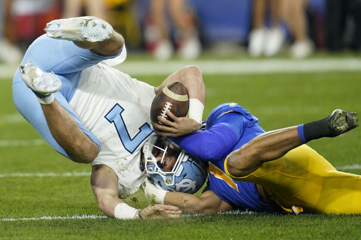 North Carolina quarterback Sam Howell, left, is sacked by Pittsburgh linebacker SirVocea Dennis during the first half of an NCAA college football game Thursday, Nov. 11, 2021, in Pittsburgh. (AP Photo/Keith Srakocic)