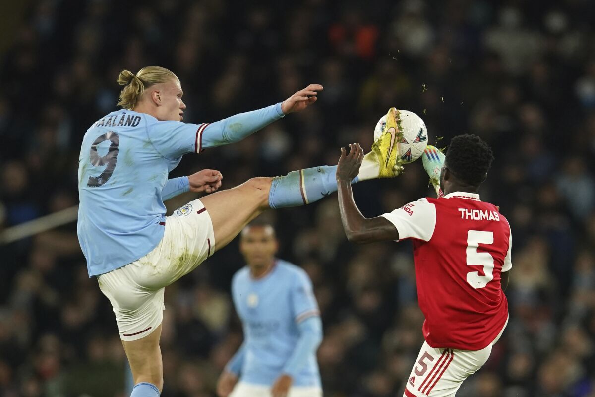 Manchester City's Erling Haaland, left, challenges for the ball with Arsenal's Thomas Partey during the English FA Cup 4th round soccer match between Manchester City and Arsenal at the Etihad Stadium in Manchester, England, Friday, Jan. 27, 2023. (AP Photo/Dave Thompson)