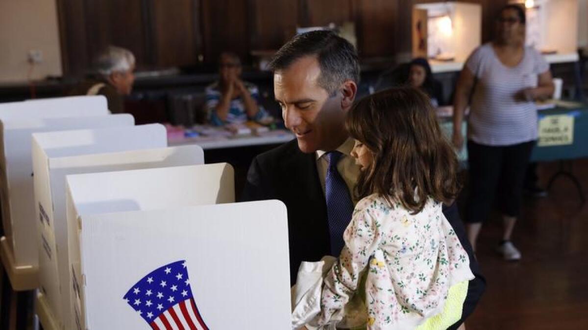Los Angeles Mayor Eric Garcetti holds his daughter, Maya, 5, while he casts his ballot Tuesday morning inside the fellowship hall at Wilshire United Methodist Church.