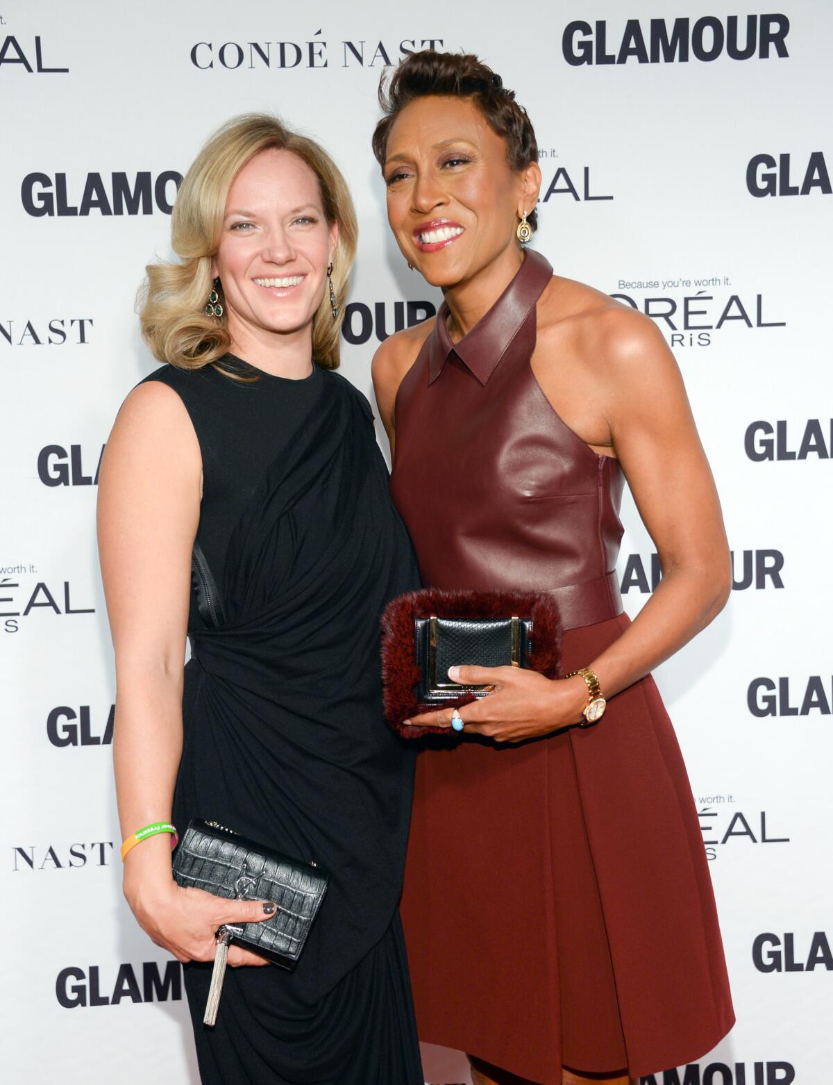 Robin Roberts wearing a blood red dress has her arm around Amber Laign in a black dress