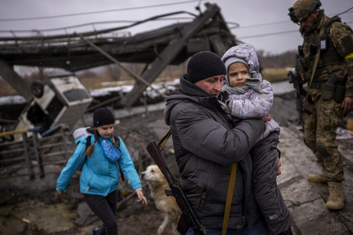 El miliciano local Valery, de 37 años, lleva a una niña en brazos mientras ayuda a una familia que huye 