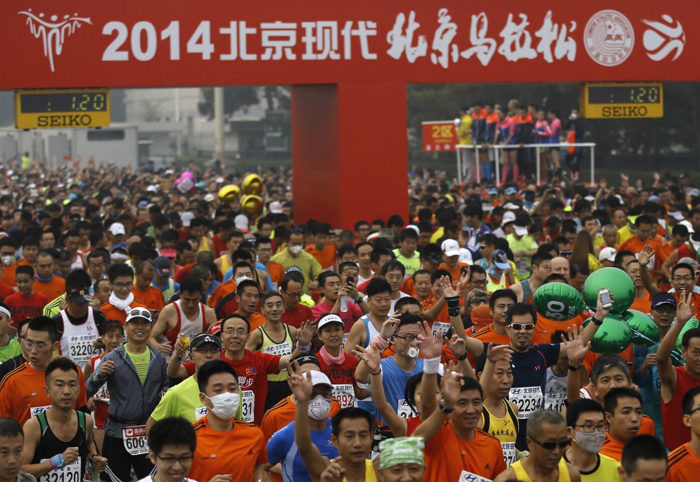 Runners, some wearing masks to protect themselves from pollutants, jog at Tiananmen Square shrouded in haze at the start of 2014 Beijing International Marathon.