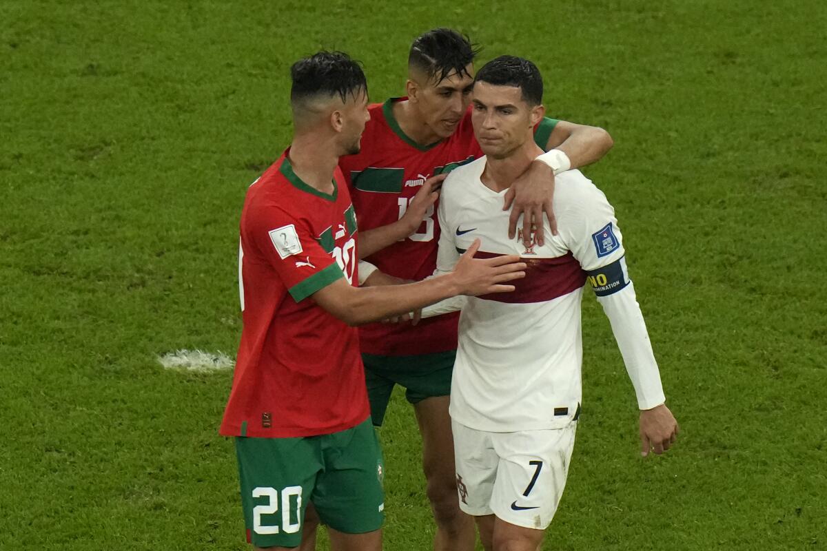 Morocco's Achraf Dari and Jawad El Yamiq comfort Portugal's Cristiano Ronaldo.