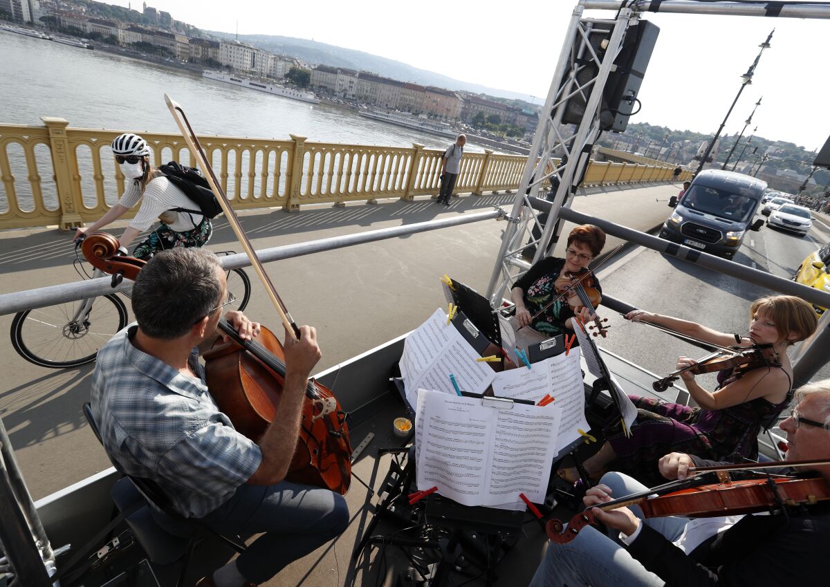 Members of the Budapest Festival Orchestra play music on the back of a truck while driving through downtown Budapest, Hungary, Wednesday June 9, 2021. The prestigious orchestra, founded and led by renowned composer Ivan Fischer, took to the streets as five members of the orchestra performed classical music to motorists and passers-by. The musical parade was aimed at encouraging Hungarians to start returning to live performances in concert halls as the pandemic wanes, after more than a year in which people were homebound and forced to take in their culture online. (AP Photo/Laszlo Balogh)