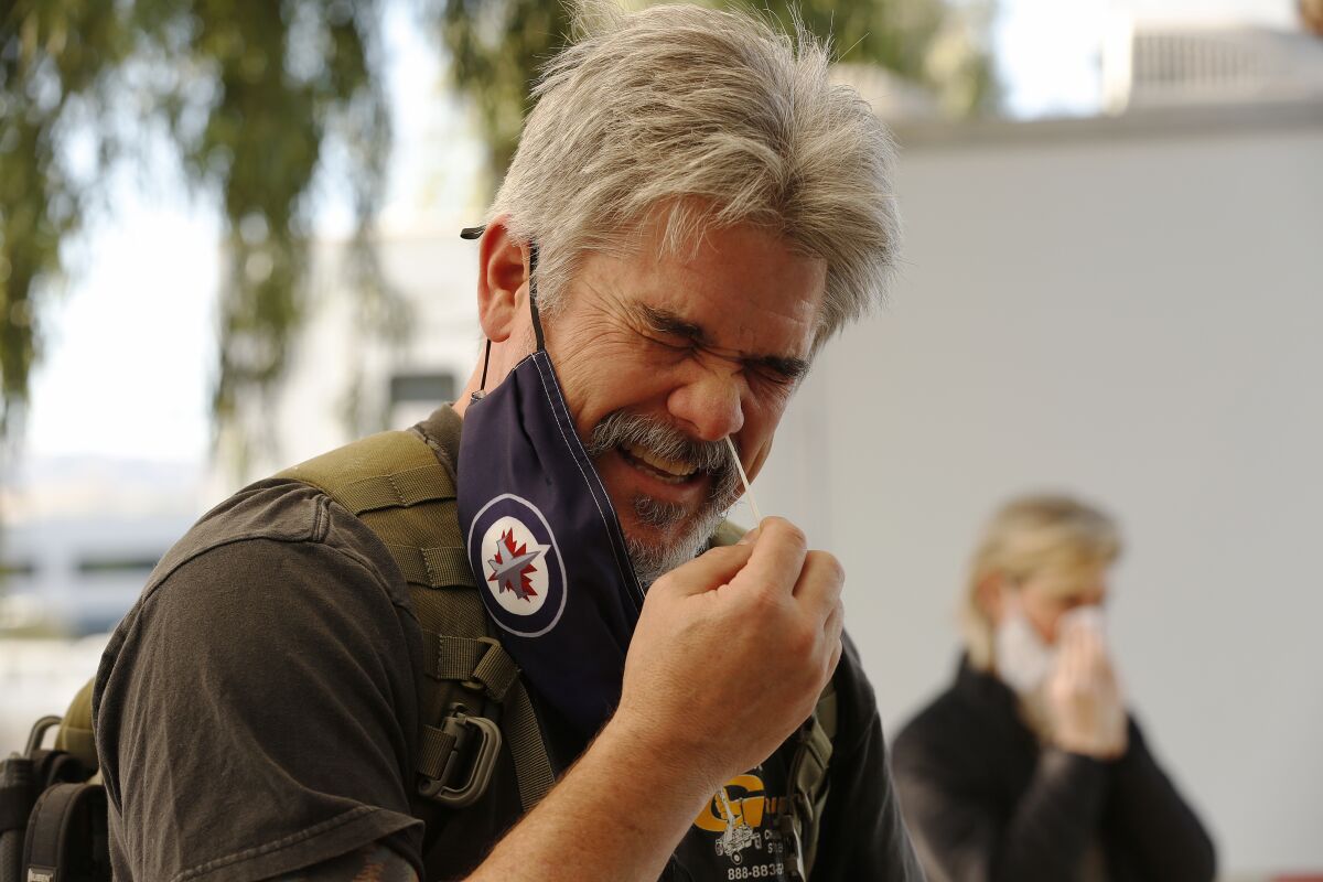 A man uses a nasal swab on himself for a coronavirus test