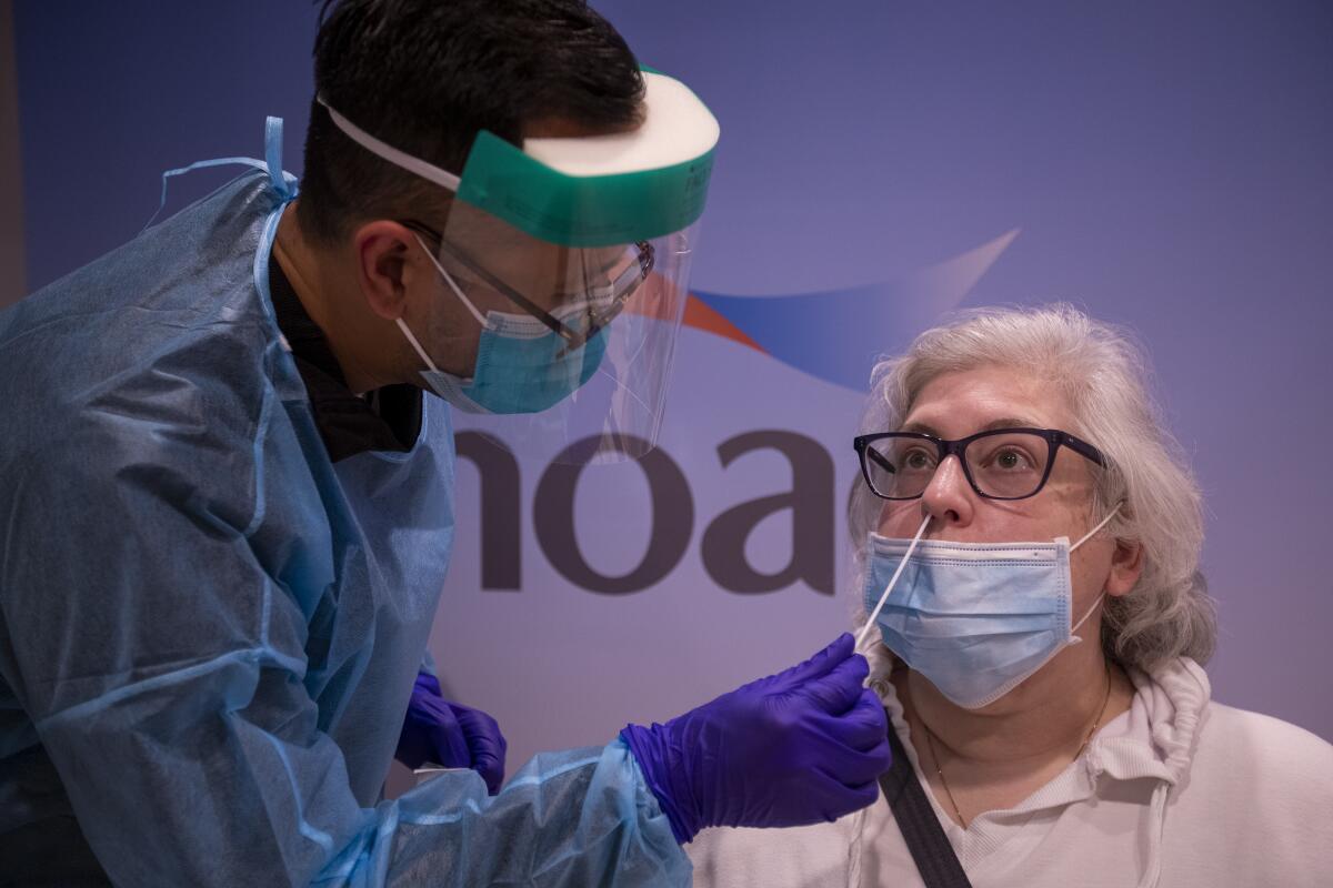 A nurses administers a COVID-19 Rapid PCR test to Terri Black of before she and her husband travel to London.