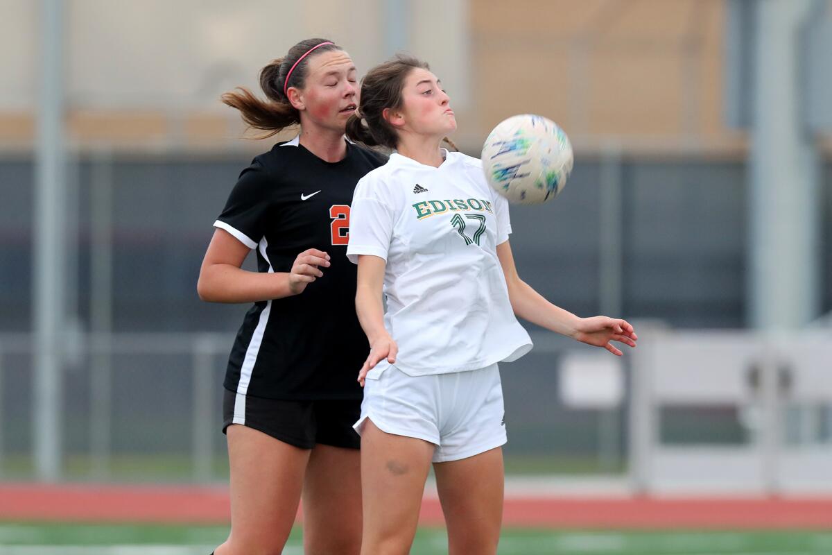 Edison's Rachel Valenzuela, right, battles with Huntington Beach's Charlotte Landis for the ball during a soccer match