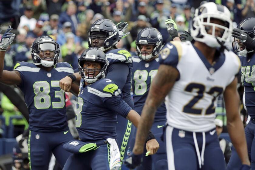 Seattle Seahawks quarterback Russell Wilson (3) celebrates next to Los Angeles Rams cornerback Marcus Peters (22) after Seahawks wide receiver David Moore, left, caught a pass for a touchdown during the second half of an NFL football game, Sunday, Oct. 7, 2018, in Seattle. (AP Photo/Scott Eklund)